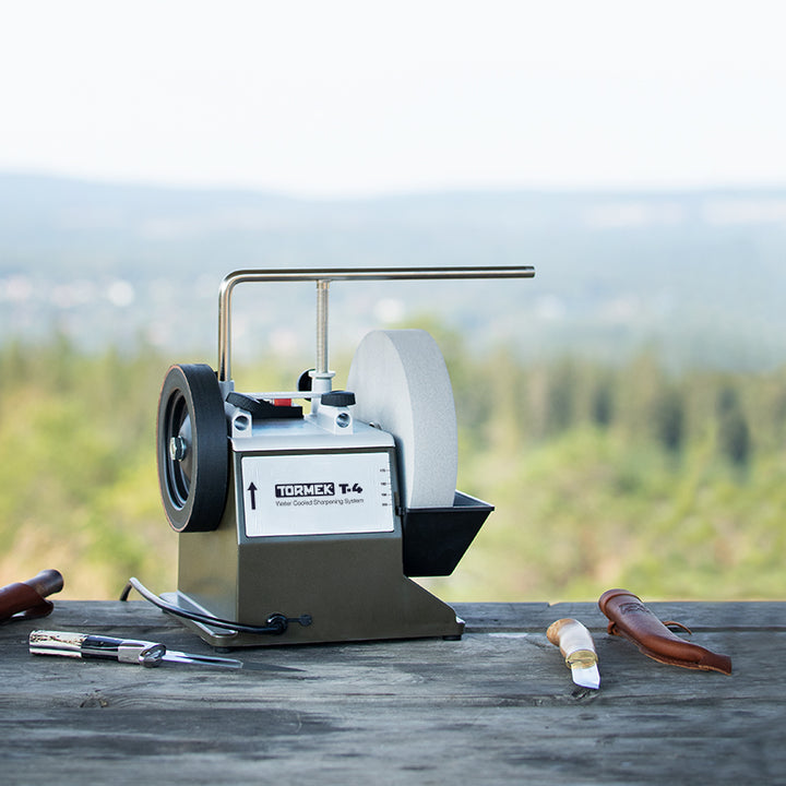 Tormek T-4BUSH sharpening machine on a wooden surface with a scenic background